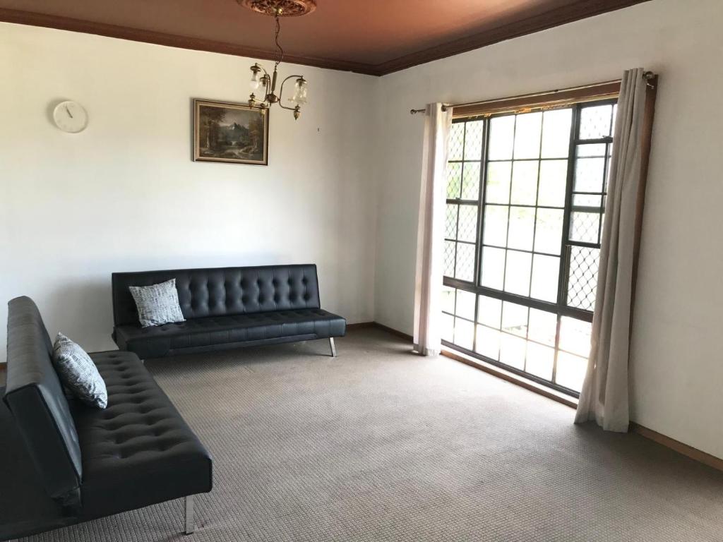 een woonkamer met een zwarte bank en een raam bij Relaxing Vintage Cottage in Corrimal