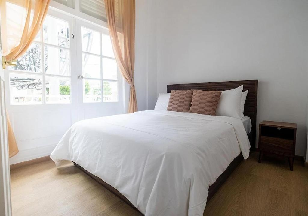 a bedroom with a large white bed with a window at Cove Service Apartments at Bugis in Singapore