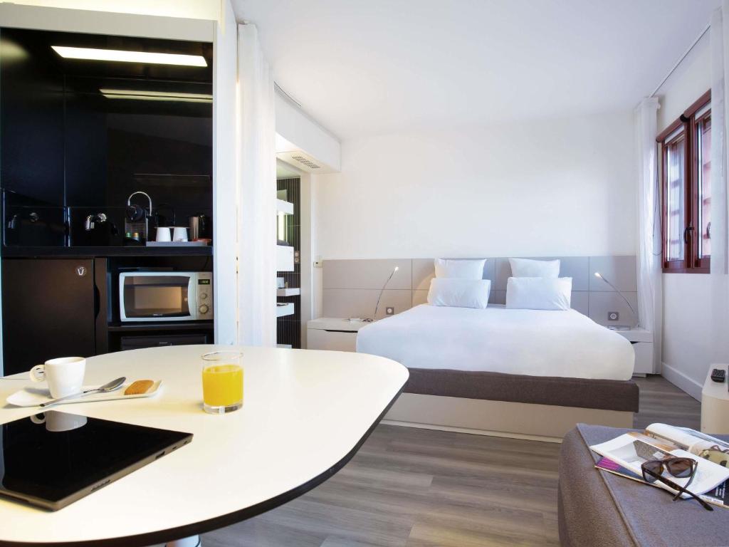 a hotel room with a bed and a table with a table sidx sidx at Novotel Suites Perpignan Centre - Grandes Suites & Confort Centre-Ville in Perpignan