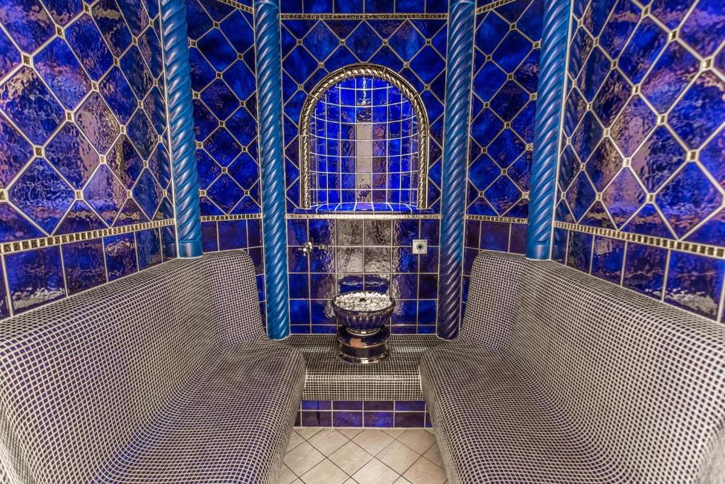 a bathroom with two benches in a room with blue tiles at Hotel Plattenhof in Lech am Arlberg