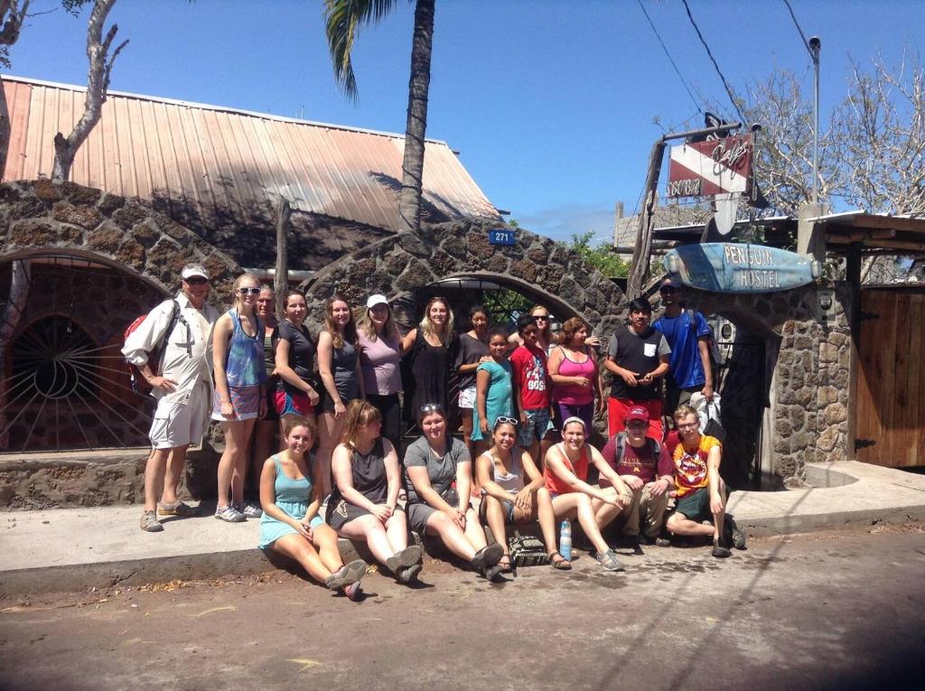 un grupo de personas posando para una foto frente a un edificio en Penguin Hostel, en Puerto Ayora