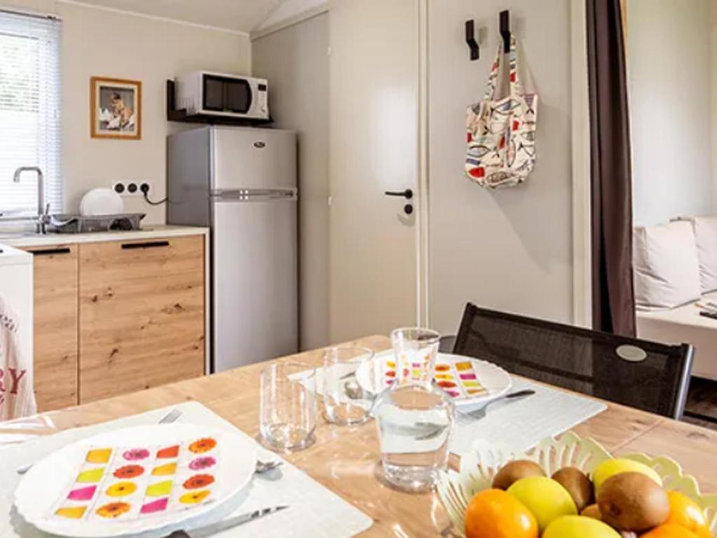 a kitchen with a table with plates of fruit on it at Mobil-home à Pordic 4 pers. avec Terrasse - API-1-52-1204 in Pordic