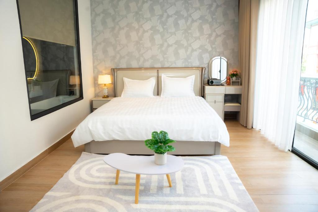 ein Schlafzimmer mit einem weißen Bett und einem Tisch in der Unterkunft T-Moon Homestay in Binh Hai