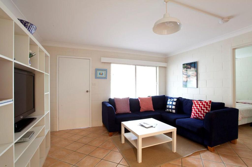 Blueys Beach Villa Manyana 24 في بلويز بيتش: غرفة معيشة مع أريكة زرقاء وطاولة