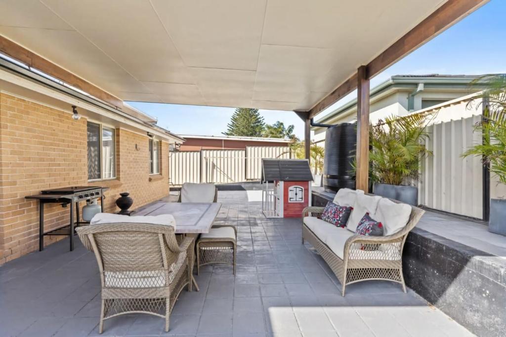 een patio met een bank, stoelen en een grill bij Sandy Serenity - Pet Friendly Beach House in The Entrance
