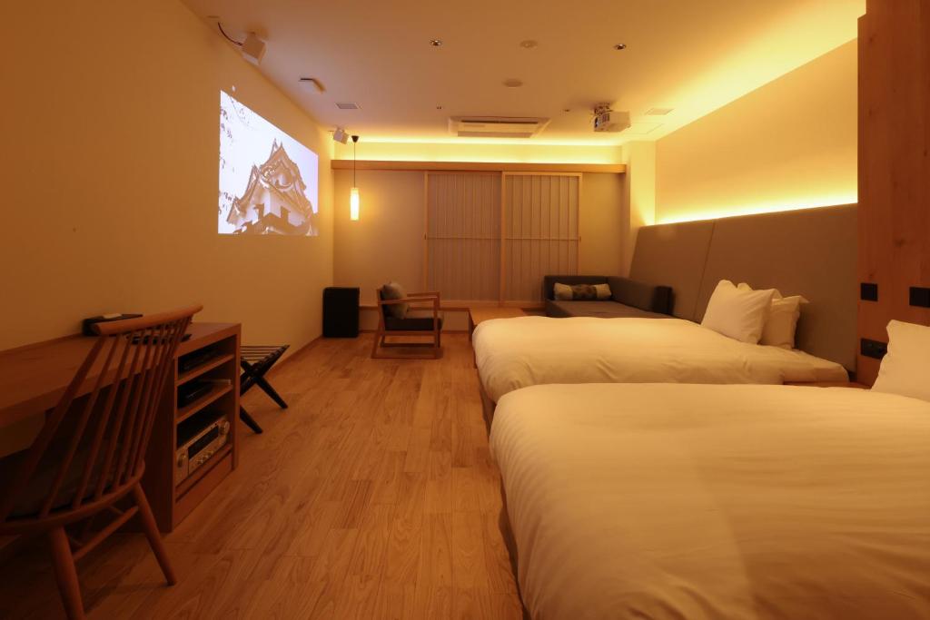 a hotel room with three beds and a flat screen tv at HATAGO HIKONE - Annex in Hikone
