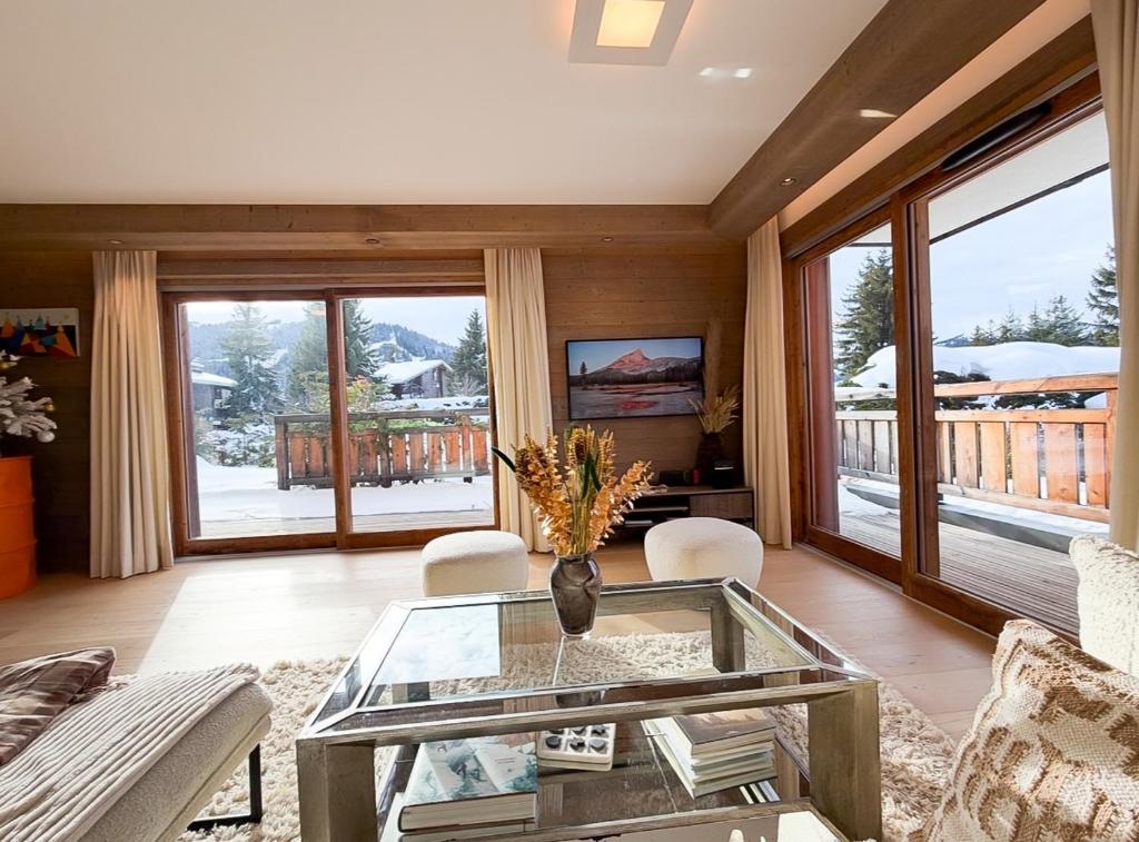a living room with a glass coffee table and a balcony at Les Chamois D’Arbois, Mont D’Arbois, Megève in Megève