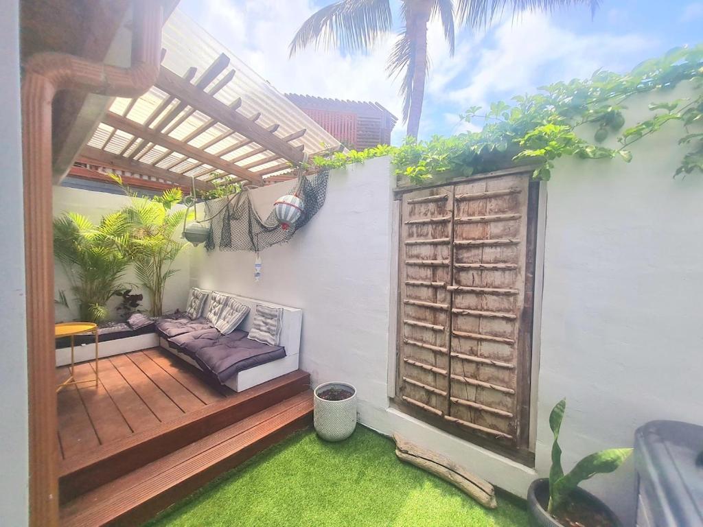 eine Terrasse mit Sofa und Holzpergola in der Unterkunft L'Echappée Tropicale - L'Echappée Mer, ma cabane de surf in L’Étang-Salé