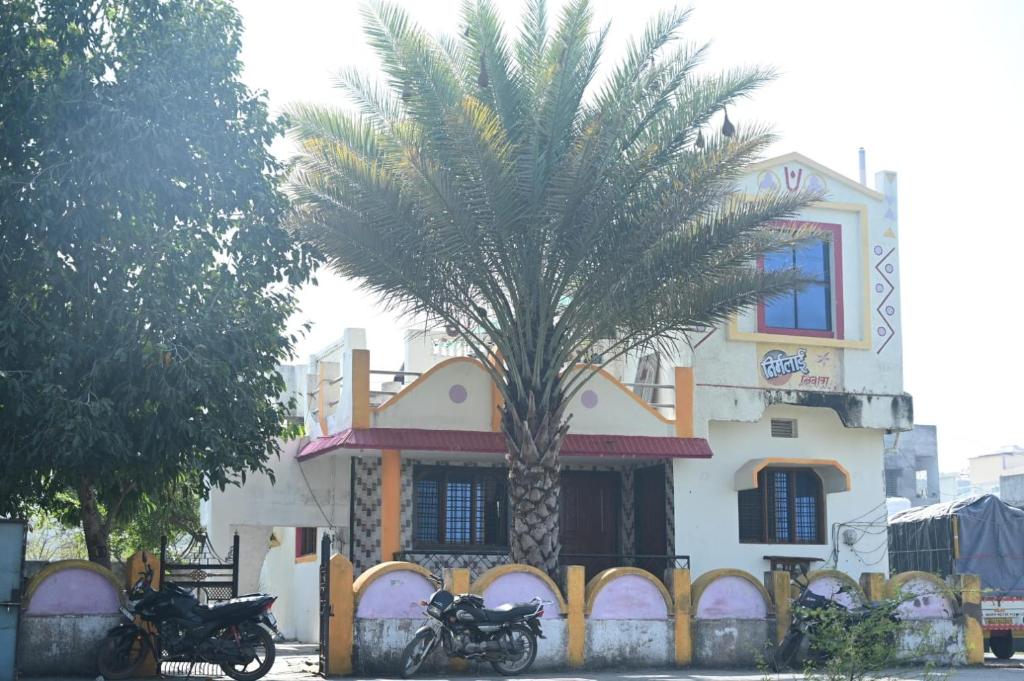 two motorcycles parked in front of a palm tree in front of a building at Hotel Nirmalai Palace Mahur in Māhūr
