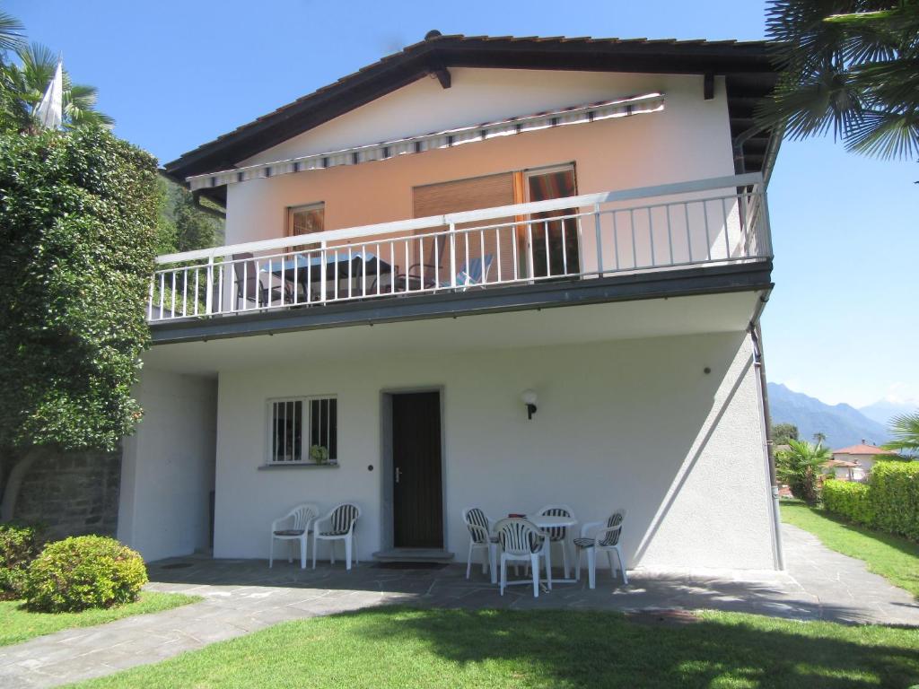 ein Haus mit einem Balkon sowie Tischen und Stühlen in der Unterkunft Casa Angela in Locarno