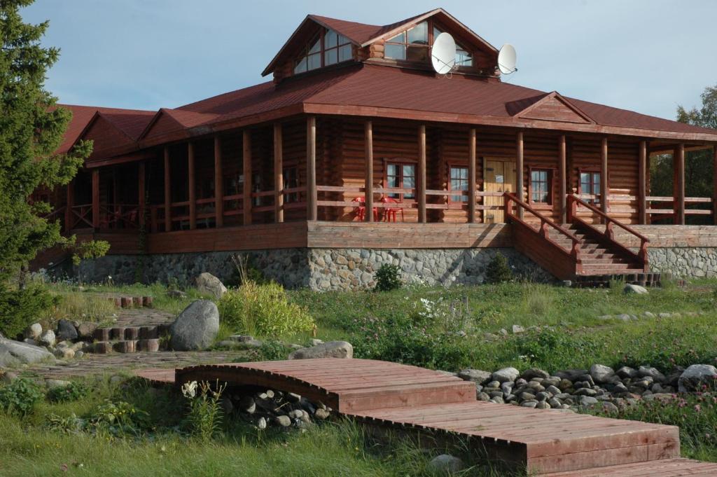 ein großes Holzhaus mit einer Brücke davor in der Unterkunft Solovki Hotel in Solowezki-Inseln