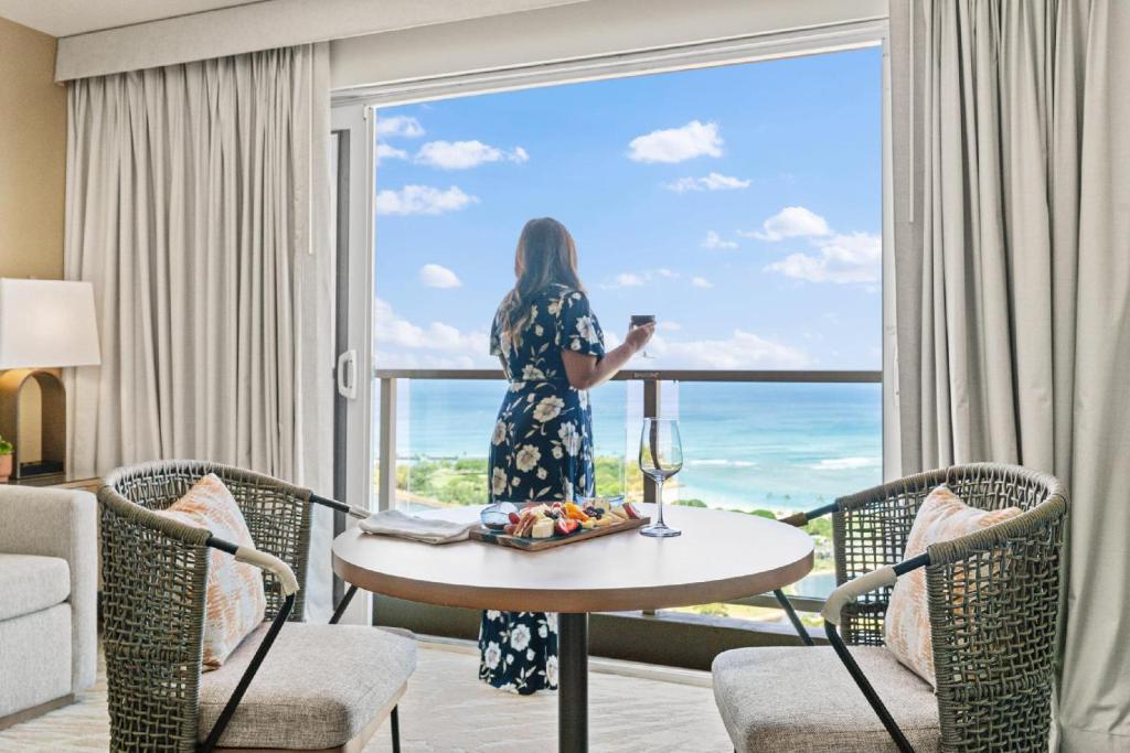 a woman standing at a table in a room with a window at Ala Moana Honolulu by Mantra in Honolulu