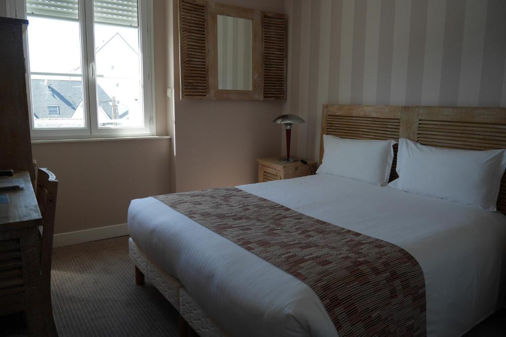 a bedroom with a large bed and two windows at Hotel Mona Lisa in La Baule