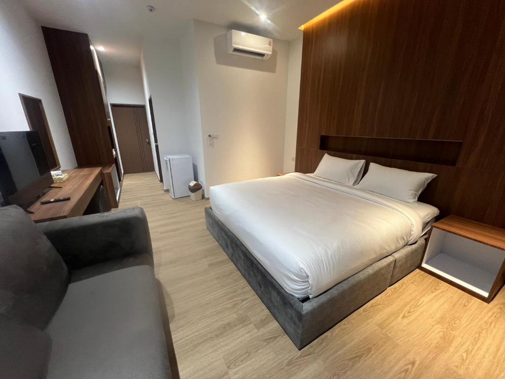 una camera d'albergo con un letto e un divano di J&P Hotel Sriracha a Ban Hua Na