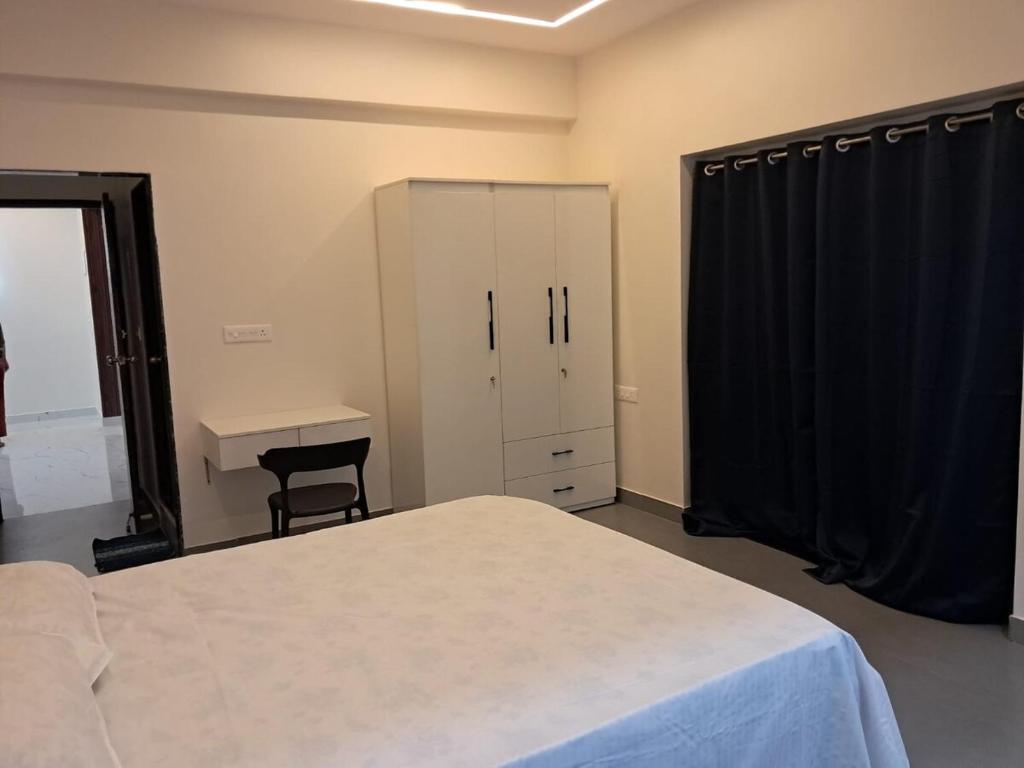 a bedroom with a bed and a desk and a cabinet at Adi's Villa in Colva