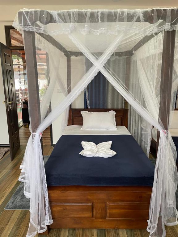 Una cama con un dosel con una mariposa encima. en sun mount adams peak, en Nallathanniya