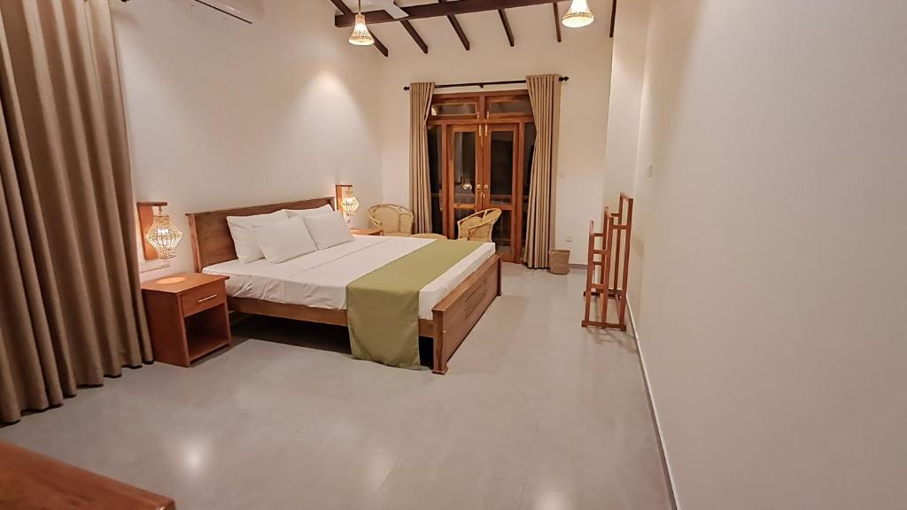 a bedroom with a bed and two tables and a window at The Clouds Ahangama in Ahangama