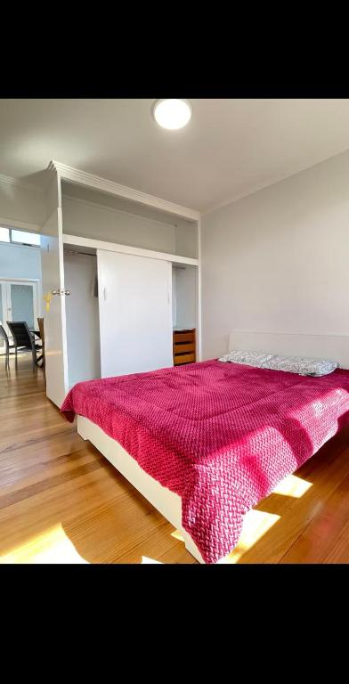 a bedroom with a large bed with a red blanket at Budget-friendly room near Sunshine Station to CBD in Sunshine