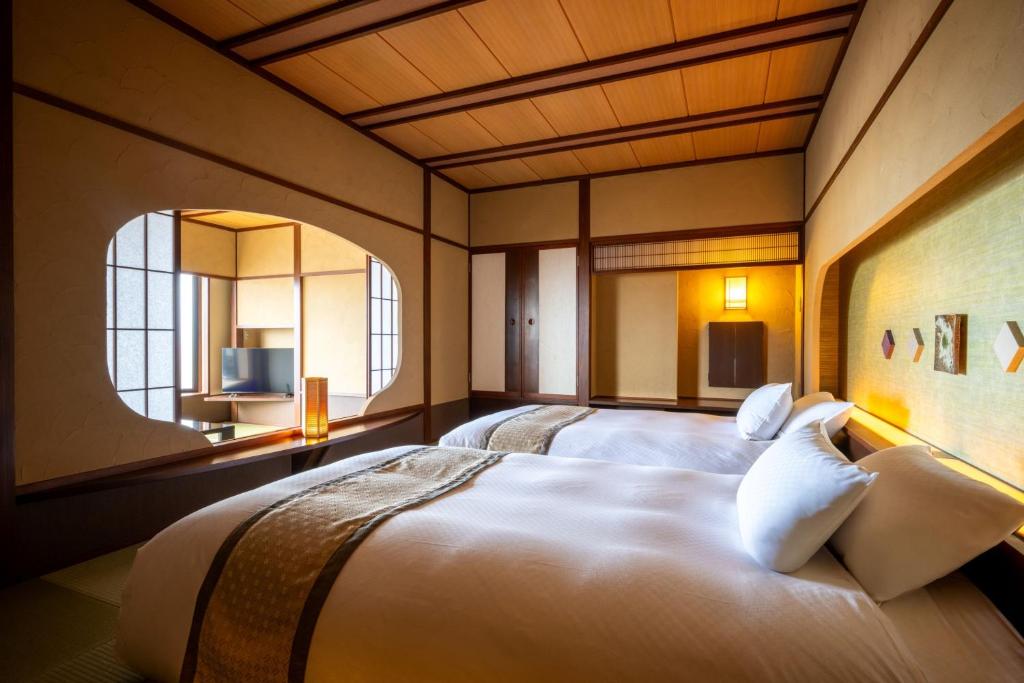 une chambre avec deux lits et une fenêtre dans l'établissement Takinoyu Hotel, à Tendō