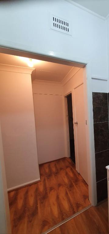 una stanza vuota con una parete bianca e pavimenti in legno di KarenResidence a Cabramatta