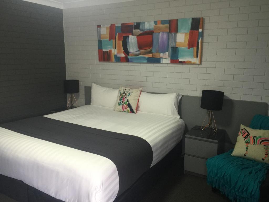 a bedroom with a bed and a painting on the wall at Blue Violet Motor Inn in Toowoomba