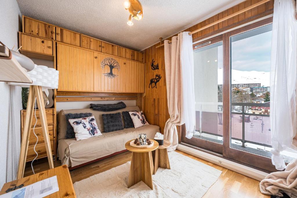 een slaapkamer met een bed en een groot raam bij Studio Champ Pérouze in La Toussuire