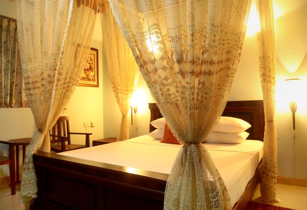 sypialnia z łóżkiem z baldachimem, zasłonami i poduszkami w obiekcie The Castle w mieście Katunayake