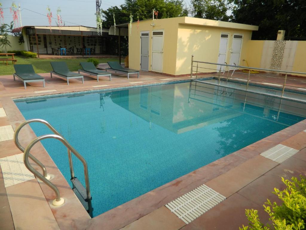 a large swimming pool with chairs and a building at The Ranthambore Samrajya Tiger Seven in Sawāi Mādhopur