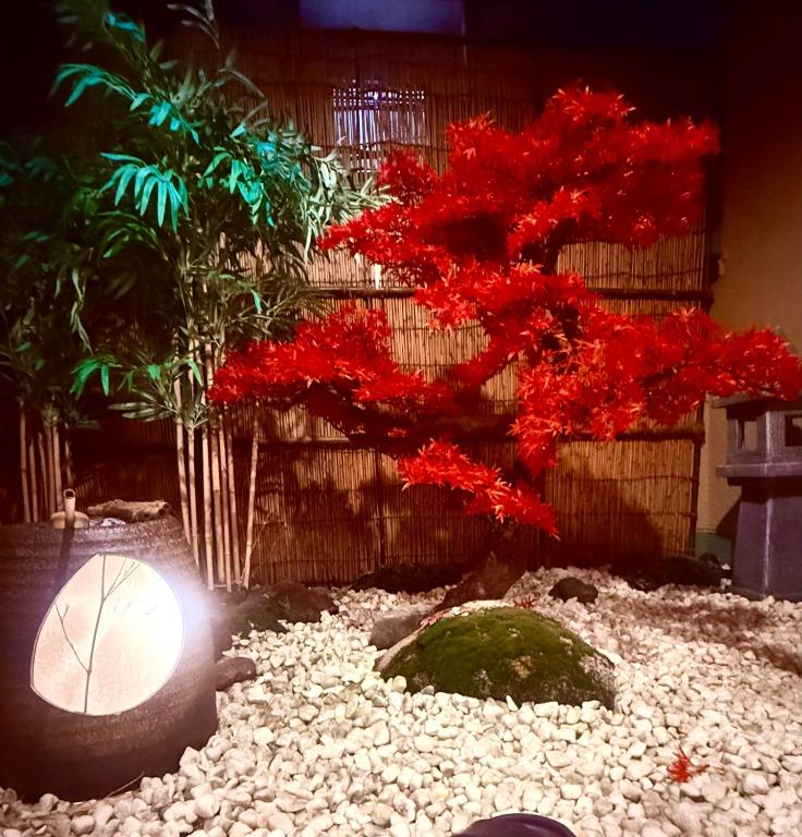 a tree with red leaves and rocks in a garden at Pine Leaf lnn 楓の宿 2号館 in Osaka
