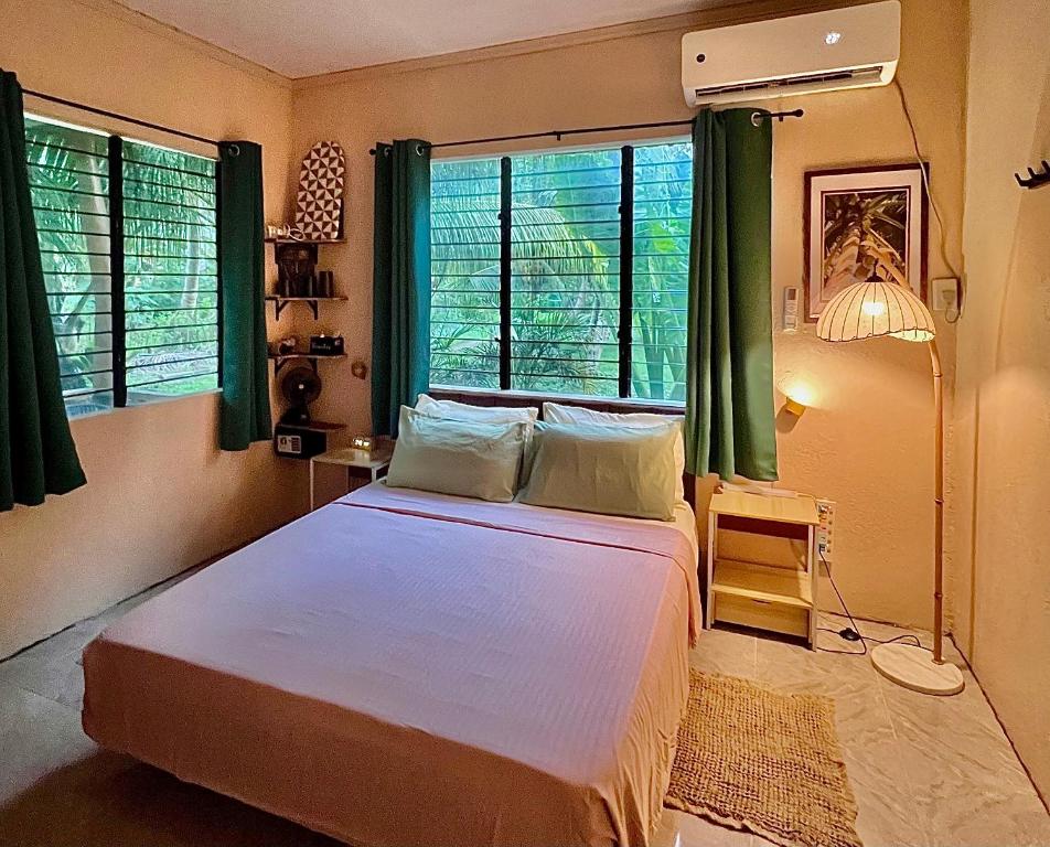 een slaapkamer met een groot bed en groene gordijnen bij Palm Haven w Starlink in Siquijor