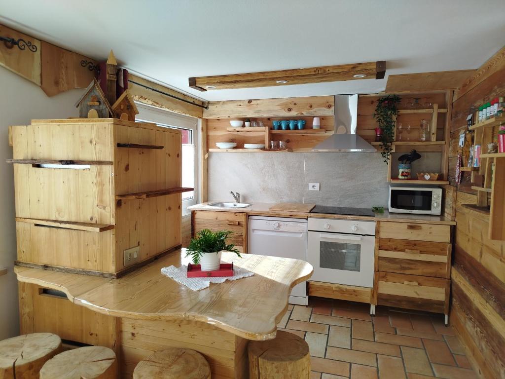 una cocina con armarios de madera y una mesa en una habitación en Botton d'oro, en Campitello di Fassa