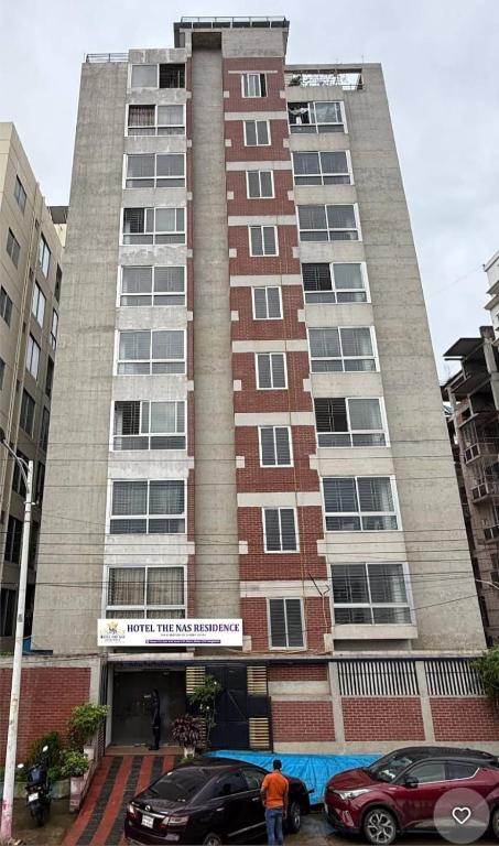 a tall building with cars parked in front of it at Hotel The NAS Residence in Dhaka