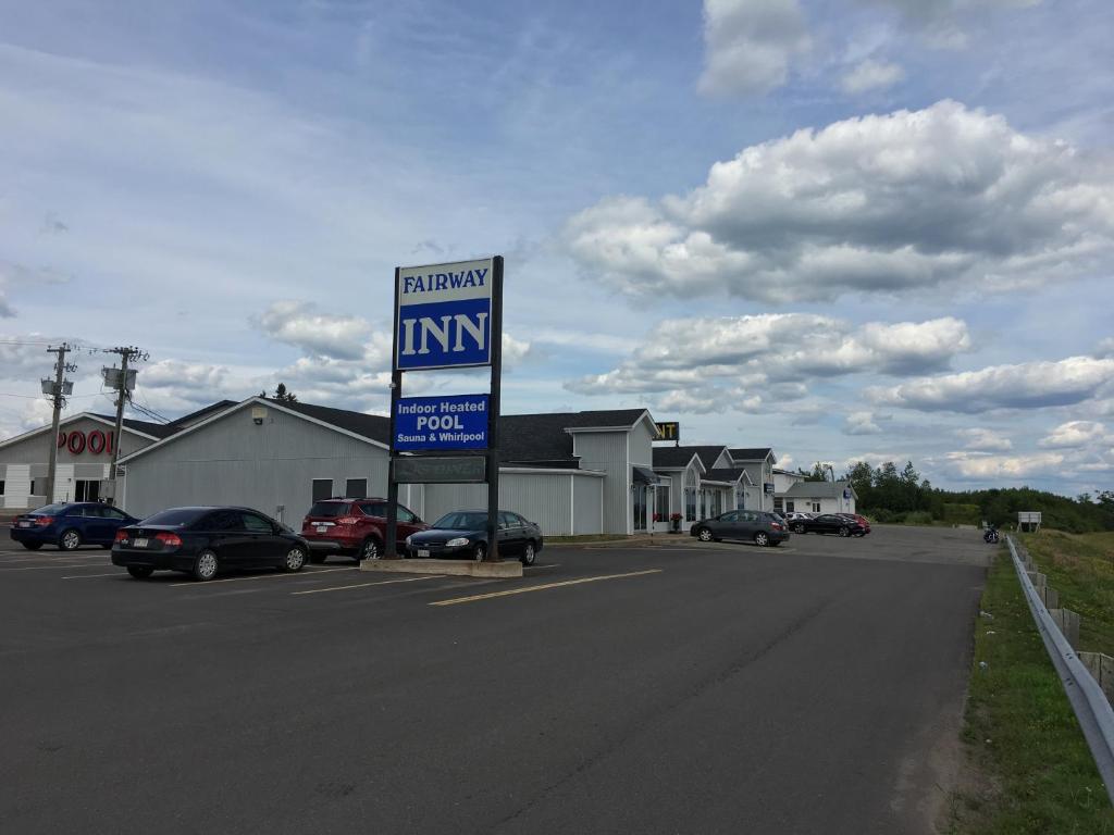 a parking lot with a sign on the side of a road at Fairway Inn in Sussex