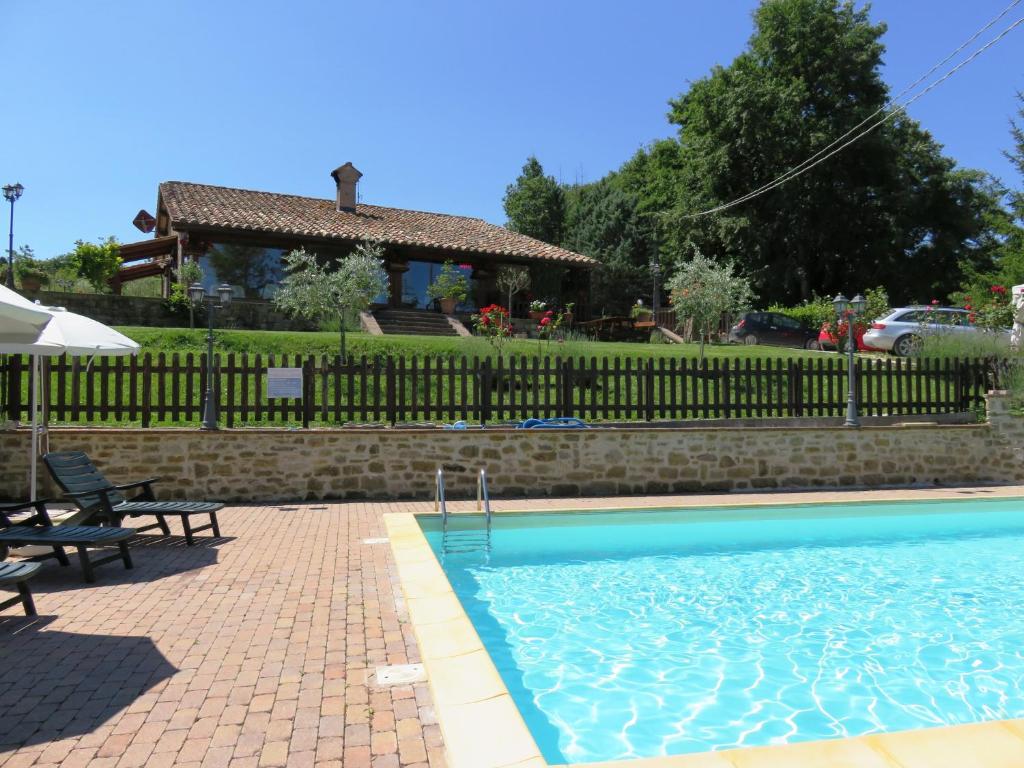 ein Schwimmbad mit einem Zaun und einem Haus in der Unterkunft Agriturismo Ponte Di Riocchio in Gubbio