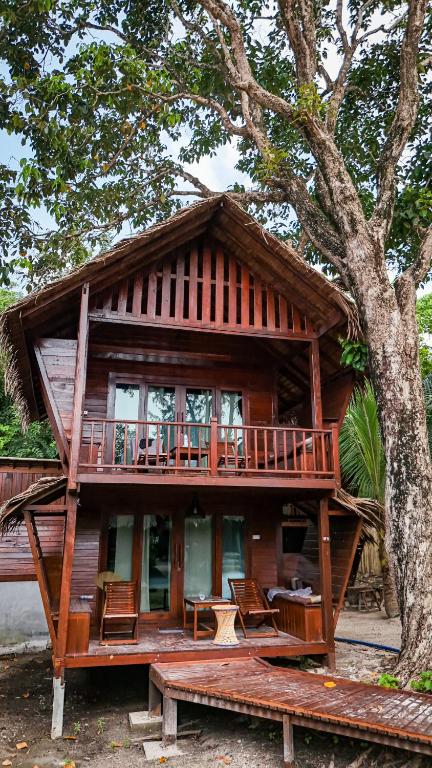 a large wooden house with a large tree at Forra Pattaya Sea View Bungalow in Ko Lipe