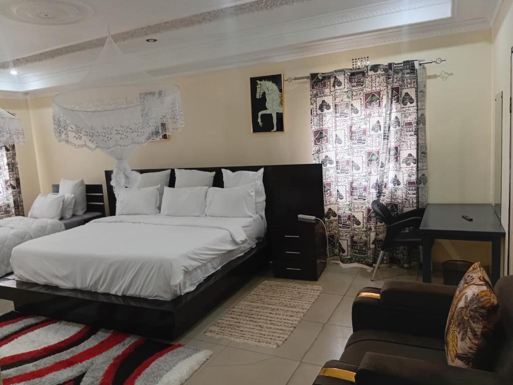 a bedroom with a large white bed and a desk at My Home Suites Area14 in Lilongwe