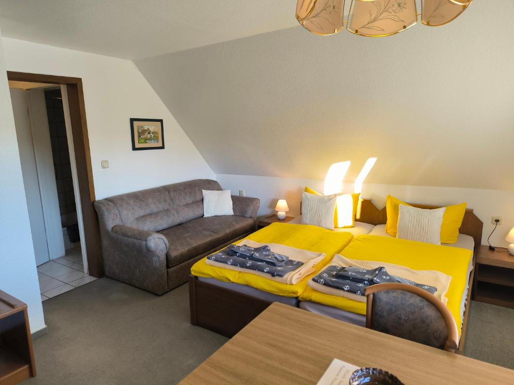 a bedroom with a yellow bed and a couch at Schwanensee App 04 in Göhren