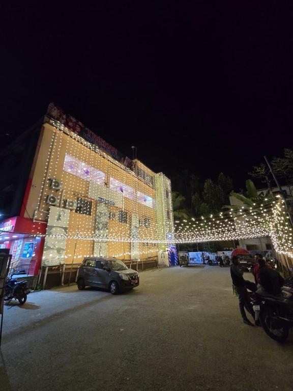 a large building with christmas lights in a parking lot at Trishan Hotel in Dhupguri