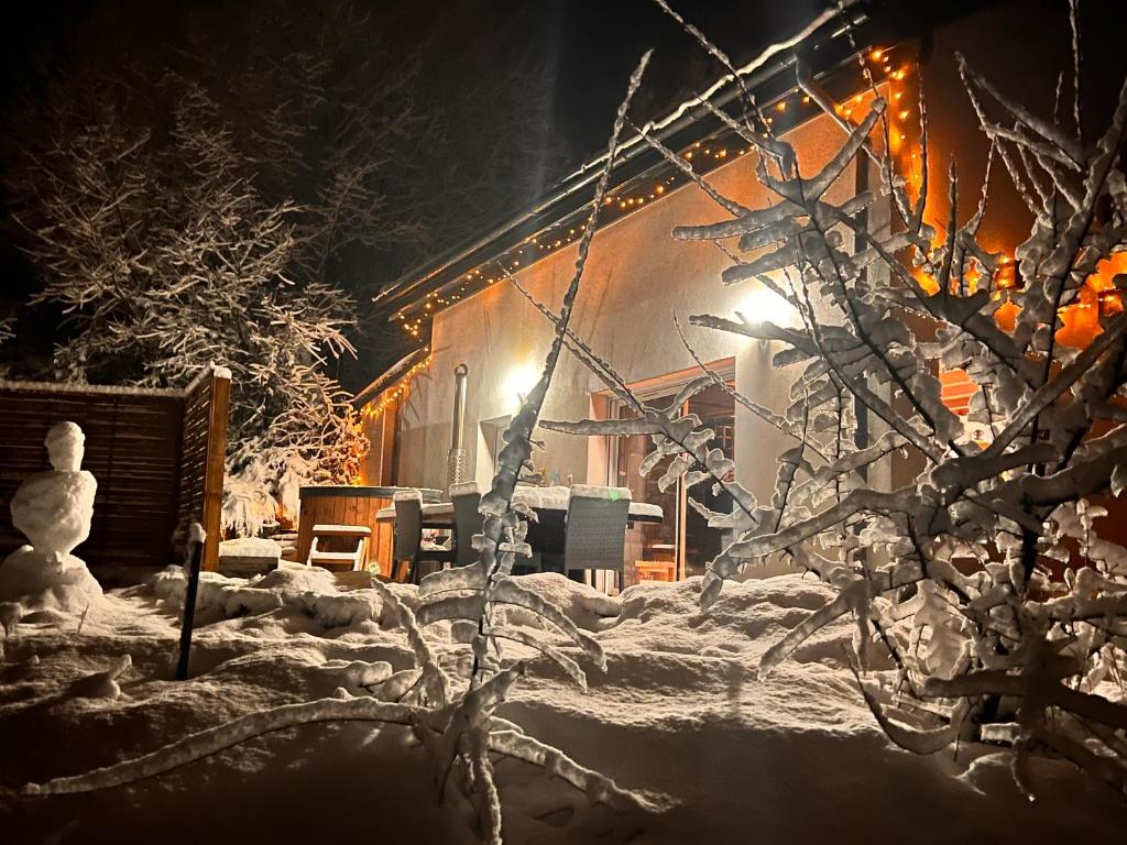 een sneeuwpop voor een huis met lichtjes bij Le HAUT DES CHANTS in Sapois