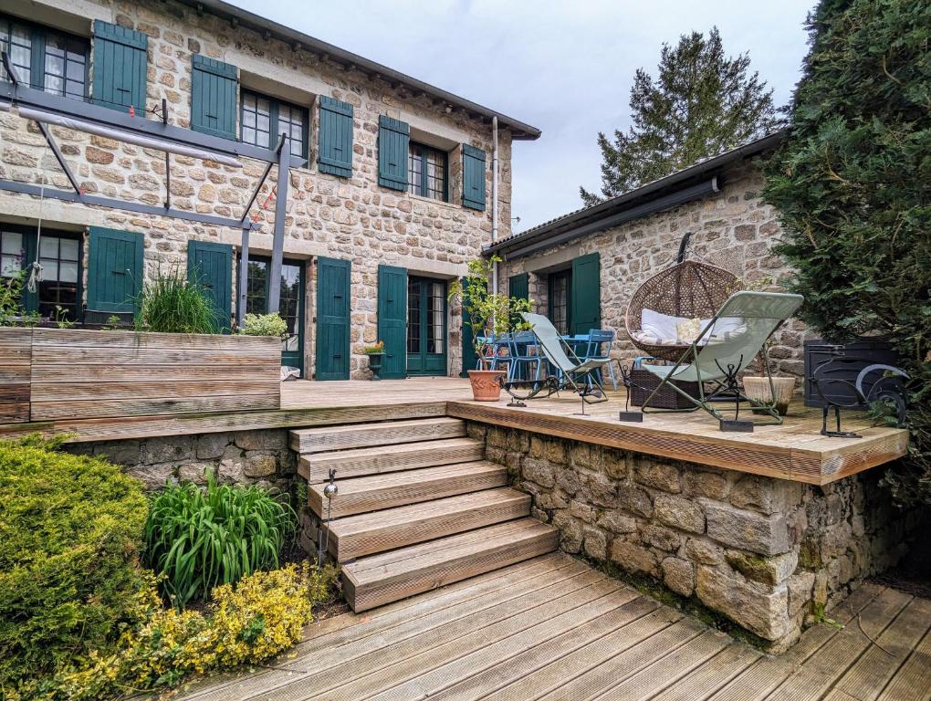 una casa con terraza de madera y un edificio en Chambre Rose of tralee, Domaine de Canard, en Saint-Romain-Lachalm