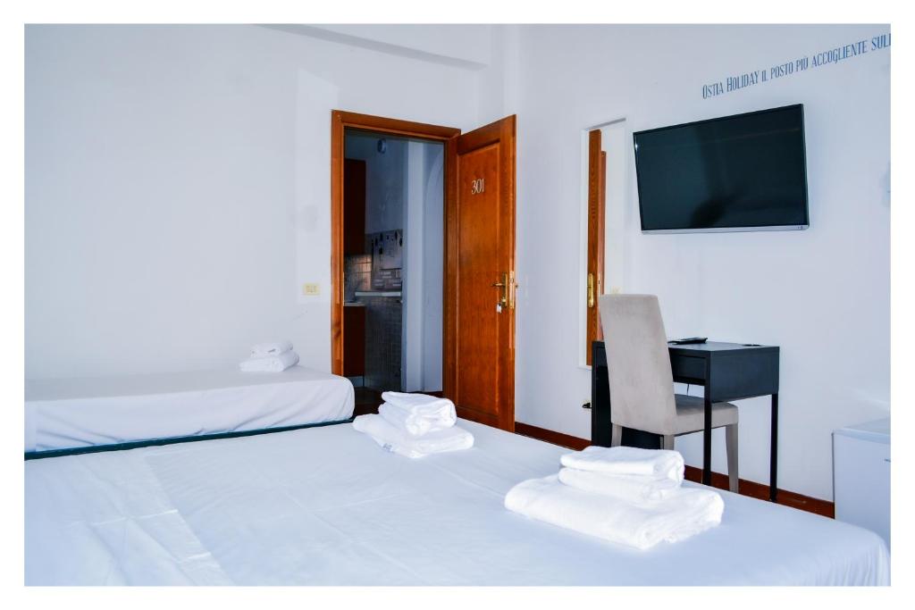 a room with two beds and a desk and a television at La Dolce Sosta in Lido di Ostia