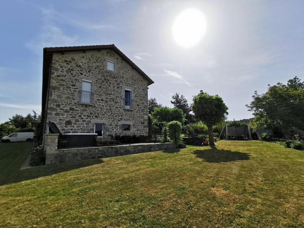 una casa in pietra con un ampio cortile erboso di Chambre Romantique, Le Suc du Pommier a Grazac
