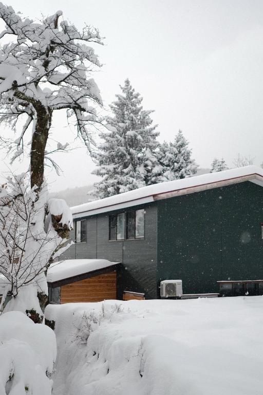 a house with snow on the roof of it at The Greenhouse in Myoko