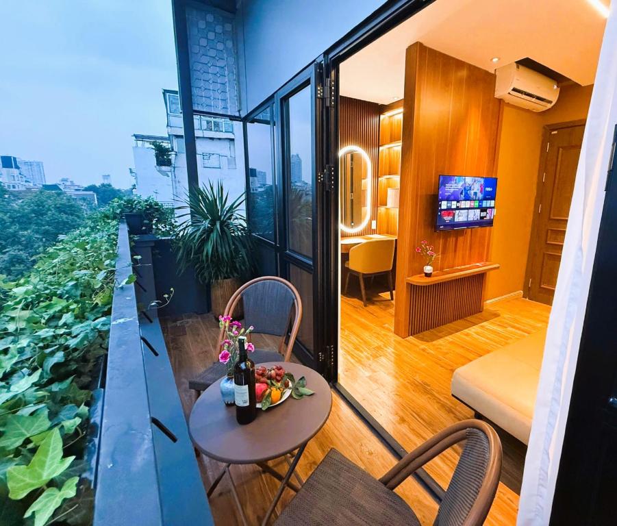 einen Balkon mit einem Tisch und Stühlen sowie einem TV in der Unterkunft Casa Valentina Hanoi Hotel in Hanoi