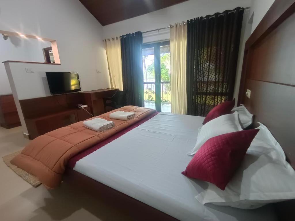 a bedroom with a large bed with red and white pillows at BharathaPuzha Resort in Kārakkād