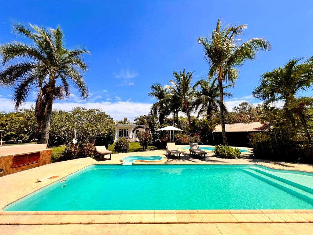 a swimming pool with palm trees and a house at Bazaar Square Lodges in Grand-Baie