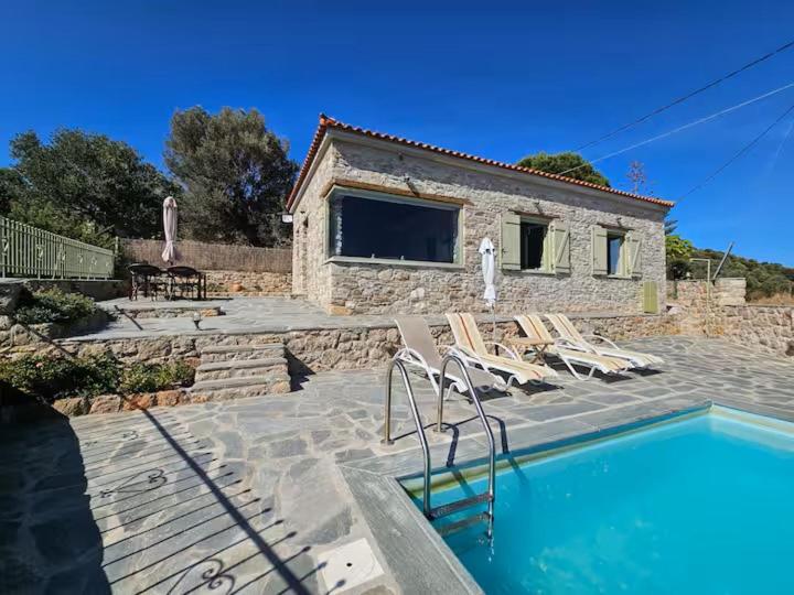 a house with a swimming pool and some chairs at Villa Rokanes Glass Stone with Pool in Kouvéllai