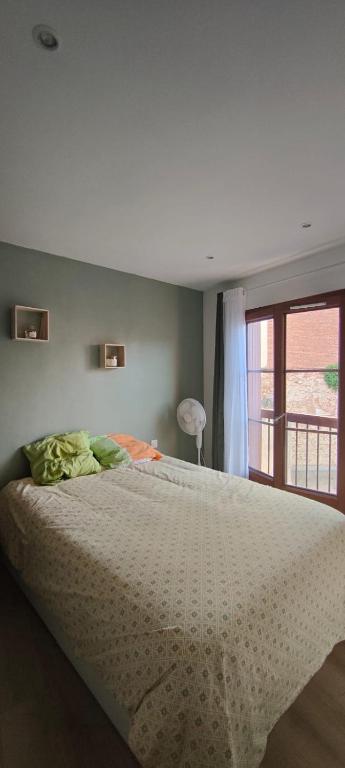 a bedroom with a bed with a white comforter and a window at Le Derroja - Perpignan in Perpignan