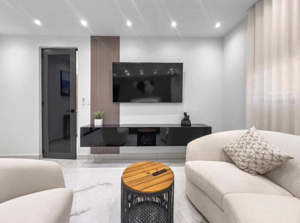 a living room with two white couches and a tv at Hyde Park 6 Couples Retreat Apt With Jacuzzi in San Juan