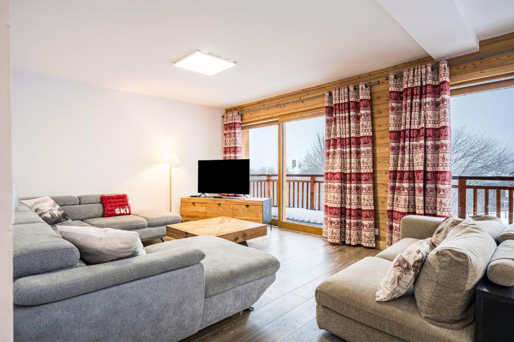 een woonkamer met 2 banken en een televisie bij Chalet Salt Lake in La Toussuire